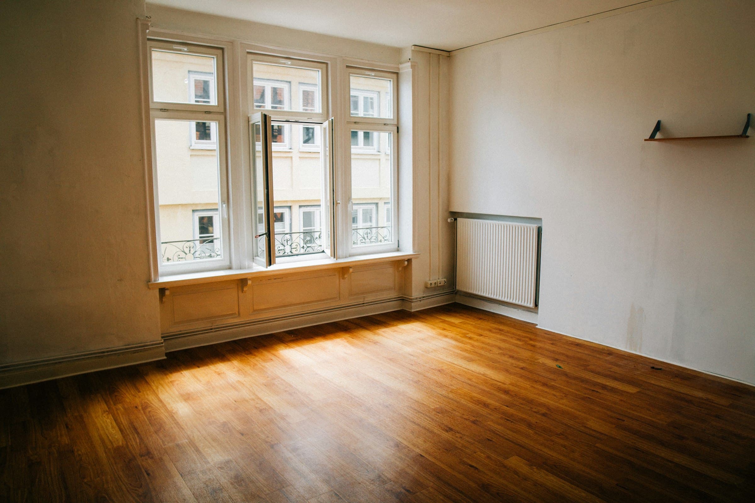 Heller Altbauraum mit frisch verlegtem Holzboden und Sonnenlicht am Fenster