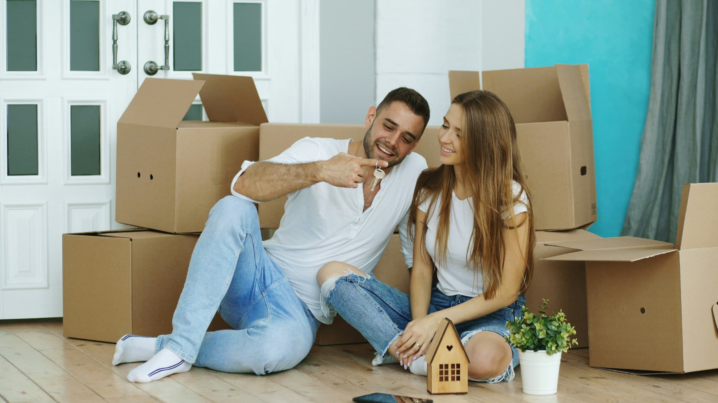 Glückliches Paar sitzt entspannt zwischen Umzugskartons in der neuen Wohnung